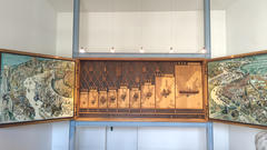 Große Wandtafel aus Holz mit illustrierten Tafeln und einer zentralen Zeitleiste mit Daten und Schiffen, die einer historischen Ausstellung oder einem Museumsstück ähnelt.