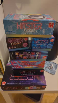 A stack of Hitster music party game boxes in different themed editions piled on a small table.