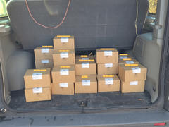 The interior of a vehicle's trunk loaded with multiple smaller labeled cardboard boxes. The trunk is open, and the arrangement of the boxes is tidy and even.