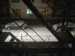 Picture of a snowy street taking from the second story, illuminated by a car driving in